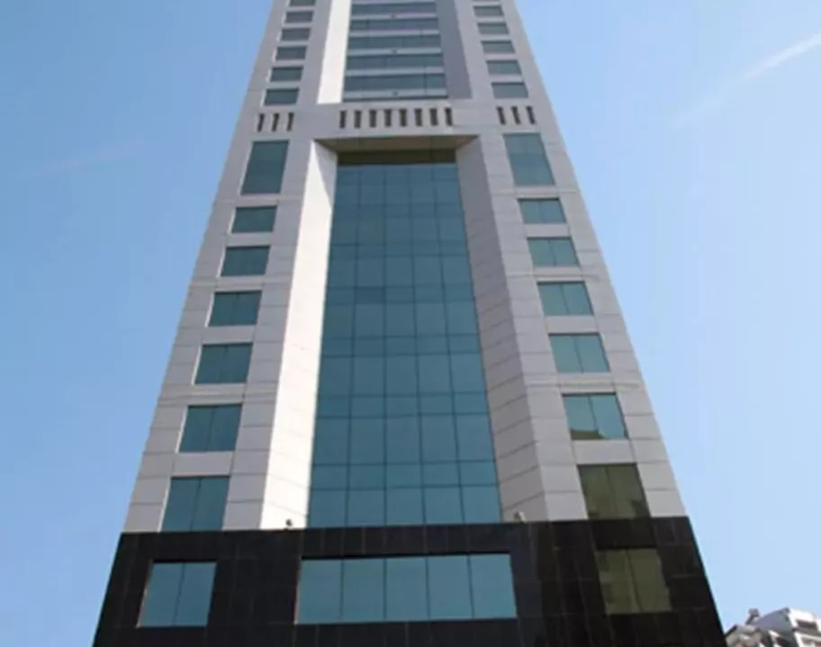 Al Habtoor Business Tower in Dubai, captured from a low angle to highlight its modern glass façade and soaring architectural presence against the clear blue sky.