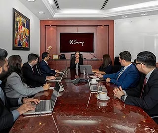A group of individuals seated around a large, polished conference table in an elegant Servcorp meeting room. at Emirates Towers, Servcorp